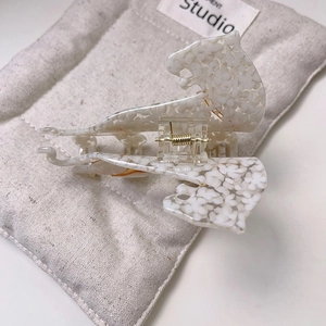 Detail of leopard-shaped cellulose acetate hair claw clip on a gray linen bag
