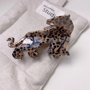 Detailed side view of a leopard-shaped acetate claw clip on a textured linen pouch