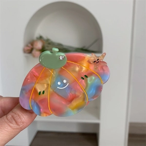 Macro view of colorful acetate pumpkin hair claw clip with smiley face and rhinestones