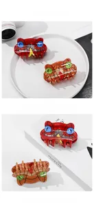 Detail of snake-shaped acetate hair claws in red and amber jelly colors with gem eyes
