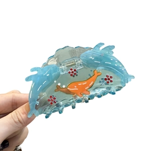 Blue ocean themed whale hair claw clip with red rhinestones held in hand