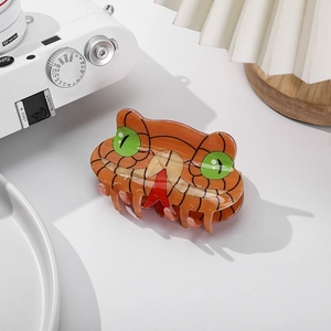 Detail of snake-shaped hair claw clip made of orange acetate with green eyes