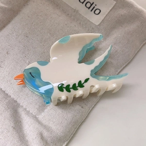 Détail de la pince à cheveux oiseau en acétate avec motifs marbrés bleus sur les ailes