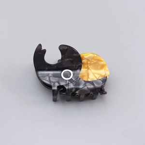 Detail of beetle-shaped acetate hair claw featuring marble texture and color contrast