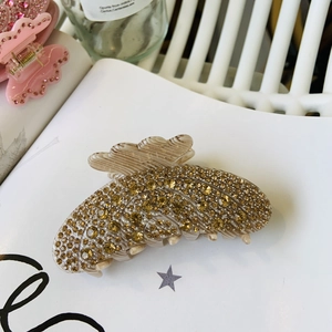Macro d'une pince à cheveux ondulée sertie de strass ambrés sur un livre blanc