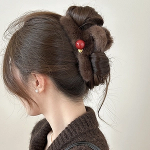 Detail view of large faux fur hair claw clip in dark brown with a red sphere ornament