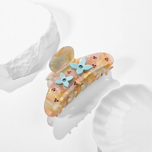 Molla per capelli ambra marmorizzata con fiori di strass blu su sfondo di pietra bianca