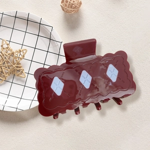 Pince à cheveux rouge foncé en forme de biscuit avec losanges blancs sur fond beige