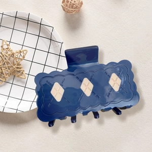 Gros plan sur une pince à cheveux bleu foncé avec motifs de losanges sur fond texturé