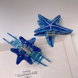 Detail of blue starfish hair clips in acetic acid marble texture with metal spring