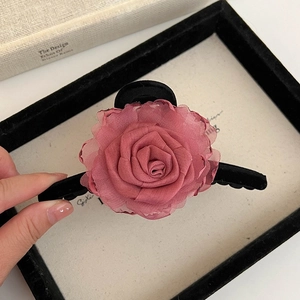 Détail d'une pince à cheveux rose en mousseline posée sur un cadre noir élégant