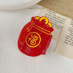 Detail of red acetate claw clip in lucky bag shape with yellow Fu character