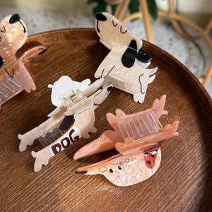 Chic dog-shaped acetate hair claws in various colors displayed on a wooden tray