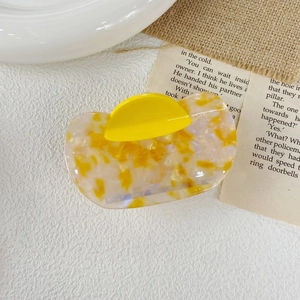 Detailed top view of a yellow marble patterned acetate hair claw clip for elegant styling