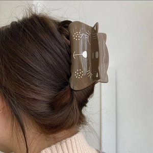 Brown cat-shaped acetate hair claw clip for women shown holding a high ponytail