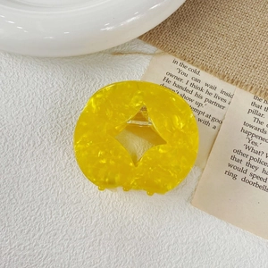 Close-up of a hollow circular yellow acetate hair claw clip with amber marble texture