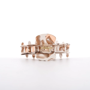 Detailed close-up of marble texture on acetate hair claw clip with golden metal spring