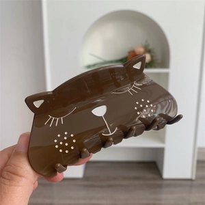 Detailed view of the dark brown acetate cat hair claw clip with minimalist feline facial pattern
