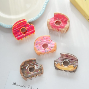 Détail de cinq pinces à cheveux en forme de donuts colorés avec pépites arc-en-ciel