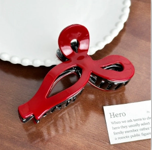 Macro detail of the glossy red resin hair claw clip with a sleek hollowed-out design