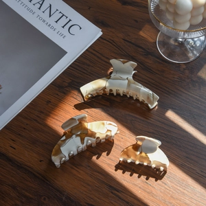 Three-piece acetate hair claw set with brown and cream marble pattern in natural window light