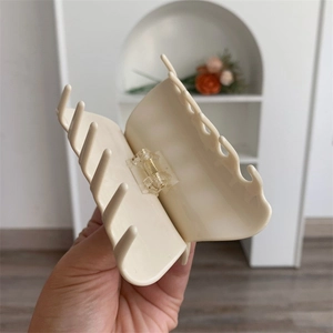 Close-up of cream acetate hair claw clip showing durable spring mechanism and smooth finish