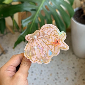 Pink acetate shell hair claw clip with starfish and pearl details for a seaside ocean look