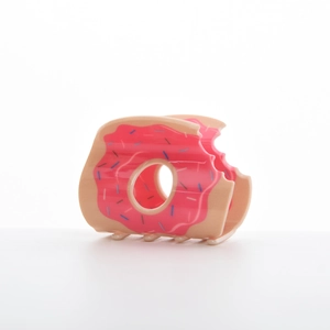 Détail d'une pince à cheveux donut rose avec base crème et glaçage aux vermicelles colorés