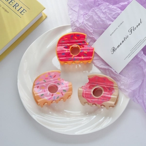 Détail de trois pinces à cheveux en forme de donuts colorés sur une assiette blanche