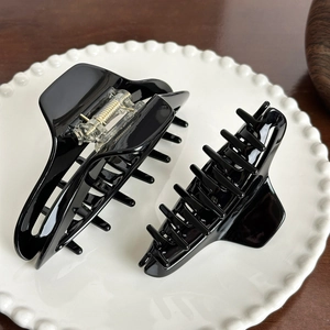 Pinces à cheveux élégantes en acétate noir brillant présentées sur une assiette en céramique