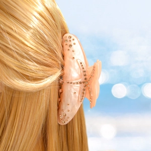 Detailed view of light orange starfish hair claw with sparkling rhinestones on blonde hair