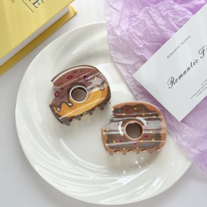 Détail de deux pinces à cheveux en forme de donut avec glaçage au chocolat et pépites
