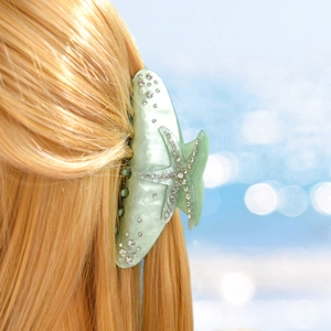 Close-up of mint green starfish hair claw with sparkling rhinestones on blonde hair