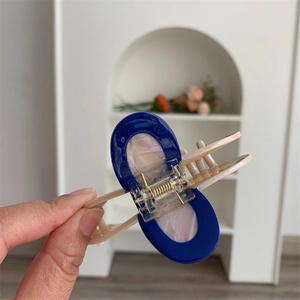 Detailed view of a large acetate claw clip featuring blue oval panel and pearl inlay
