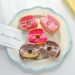 Détail de cinq pinces à cheveux donuts avec granulés colorés dans un plat décoratif