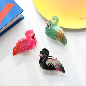 Detailed set of three colorful flamingo hair claws in pink, green, and black acetate material