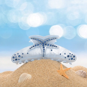 Close-up of a large pearly white shark hair claw with blue rhinestone starfish detail