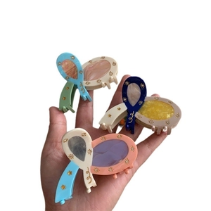 Three acetate bow hair claws with sparkling gold star accents on white background
