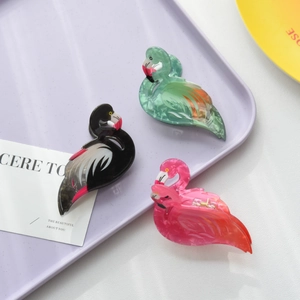 Detail of pink flamingo hair claws on a tray showing smooth acrylic texture and metal spring