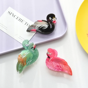 Detailed macro view of acrylic flamingo hair claws in pink, green, and black marble finish