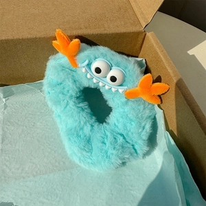 Détail d'un chouchou monstre en peluche bleu clair avec des yeux dans une boîte cadeau