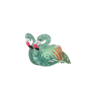 Macro detail of flamingo hair claw featuring green marble acetate and bird beak patterns