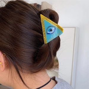 Detail of blue acetate hair claw with evil eye design and yellow vintage patterns
