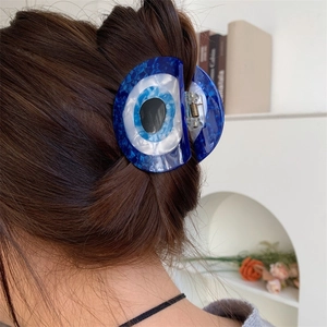 Dark blue acetate claw clip with Evil Eye design worn on long brown hair