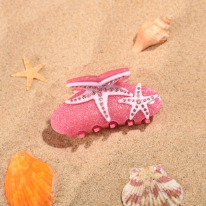 Gros plan d'une pince à cheveux étoile de mer rose avec strass sur fond de plage d'été