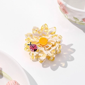 Close-up of floral acetate hair claw clip with marble texture and pink ladybug detail