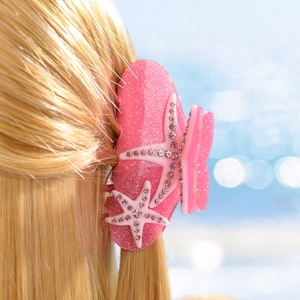 Détail d'une pince à cheveux rose pailletée avec des strass en forme d'étoile de mer
