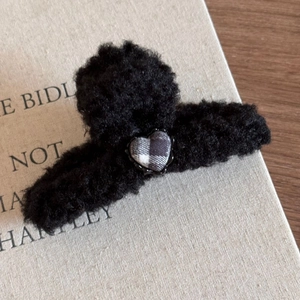 Vue détaillée de la pince à cheveux en peluche noire avec décoration en tissu à carreaux