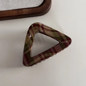 Close-up of a triangular hair claw clip featuring a classic red and green plaid pattern