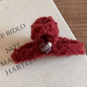 Détail d'une pince à cheveux rouge en peluche avec motif de cœur écossais pour l'hiver